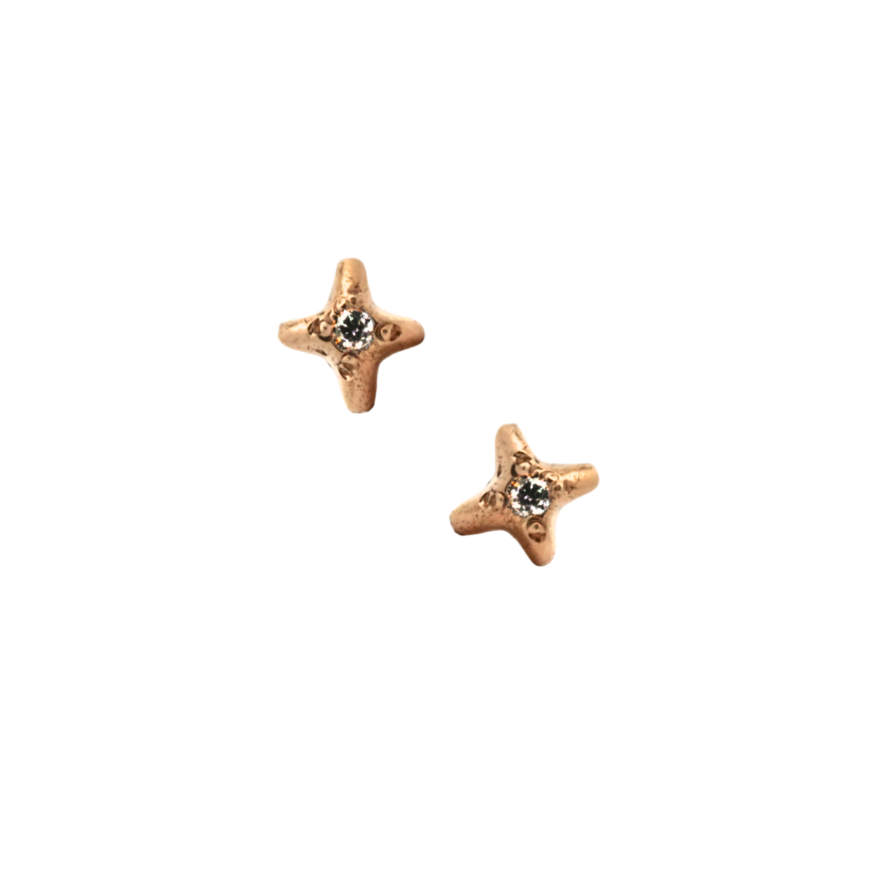 Gold star stud earrings with diamond center on black background