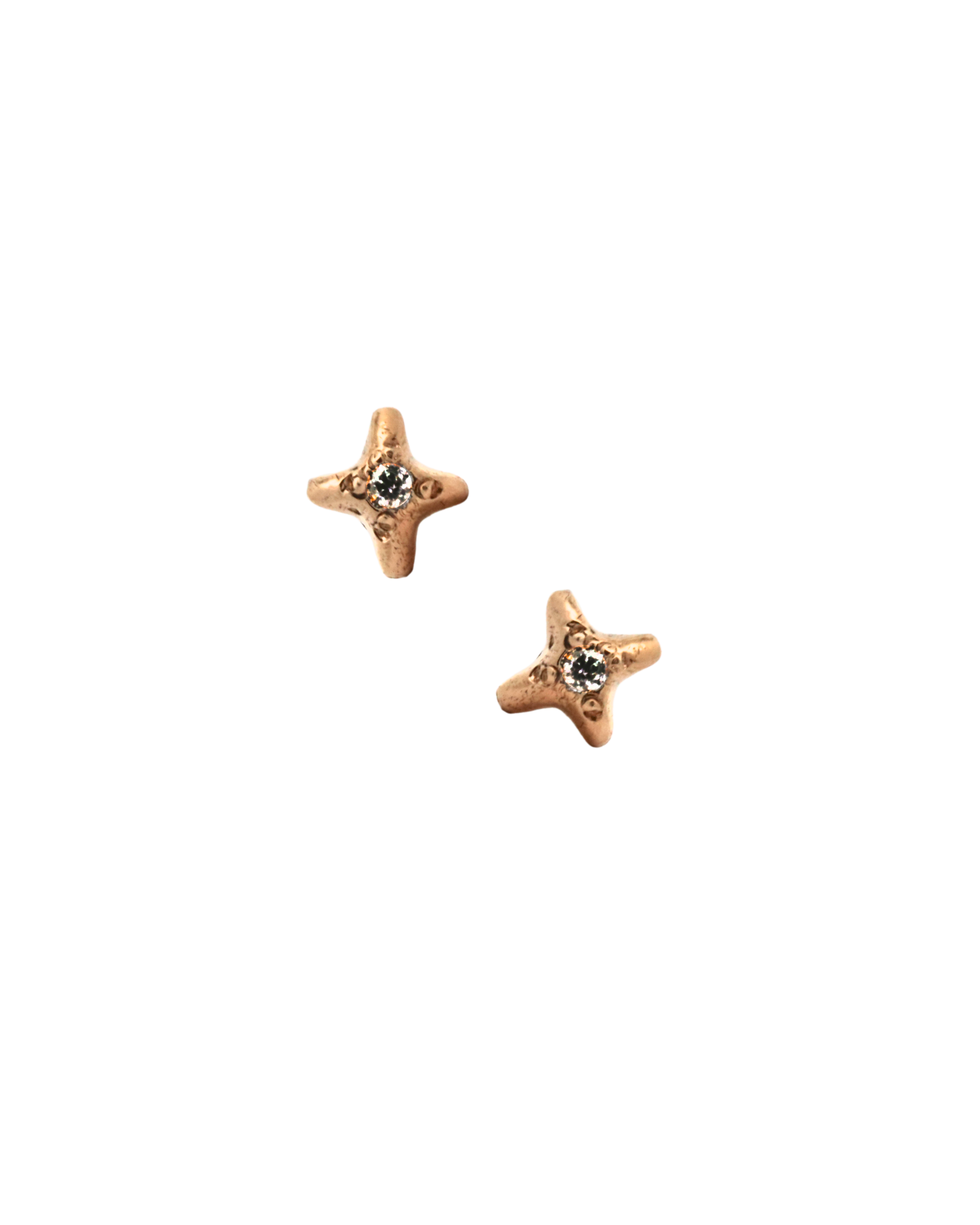 Gold star stud earrings with diamond center on black background